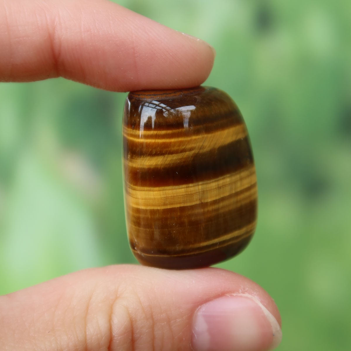 Tigerauge Handschmeichler 29mm - Selbstbewusstsein und Konzentration - Unikat Nr. 12, glänzender Tigerauge-Anhänger in der Hand gehalten