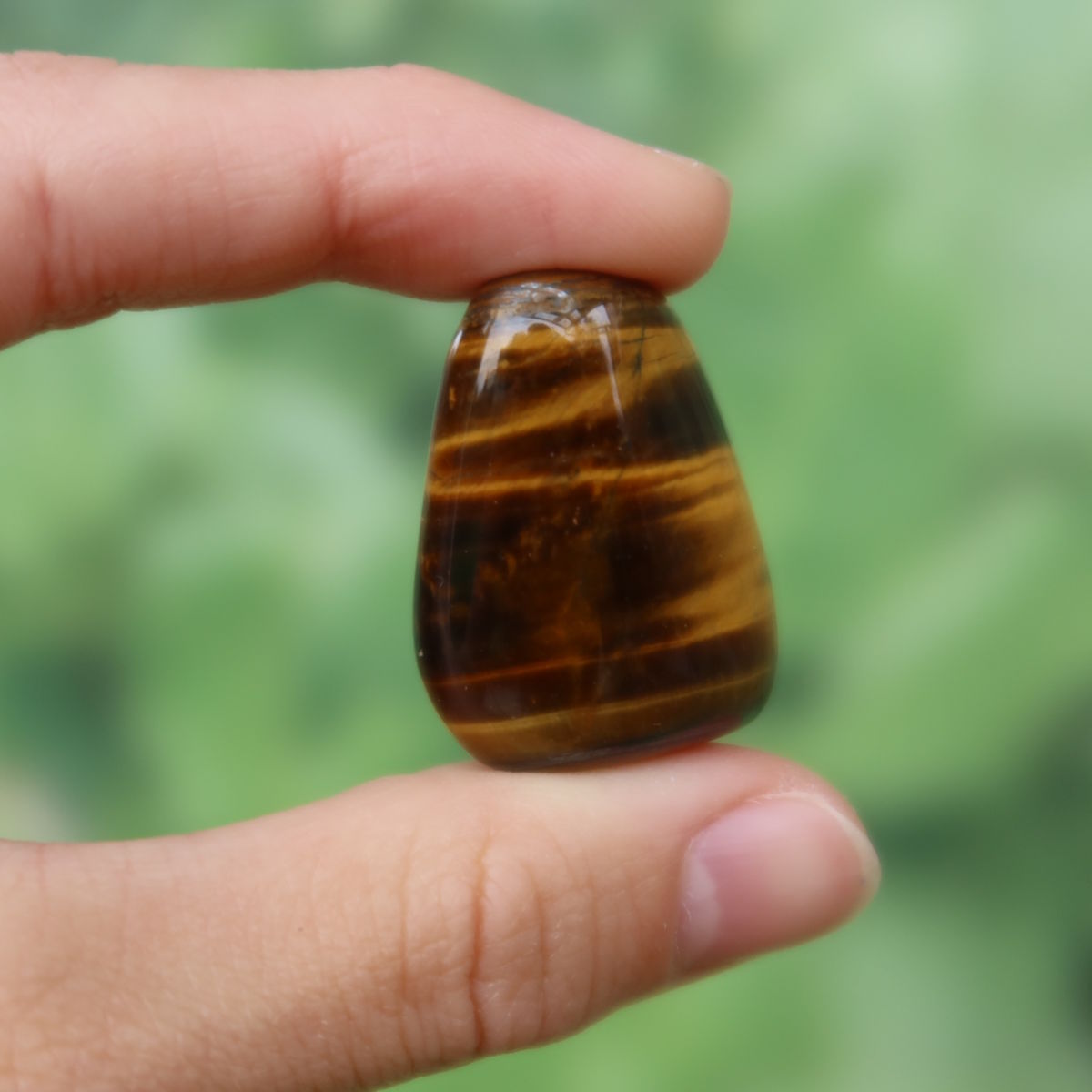 Tigerauge Handschmeichler 30mm - Selbstbewusstsein und Konzentration - Unikat Nr. 16, glänzender brauner Stein zwischen Fingern gehalten