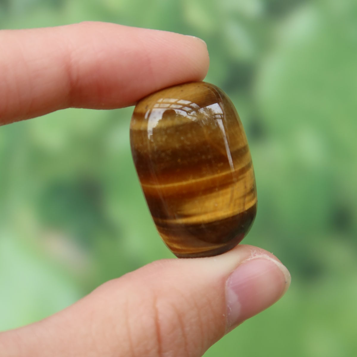 Tigerauge Handschmeichler 30mm - Selbstbewusstsein und Konzentration - Unikat Nr. 21 in einer Hand gehalten, glänzend und warm.