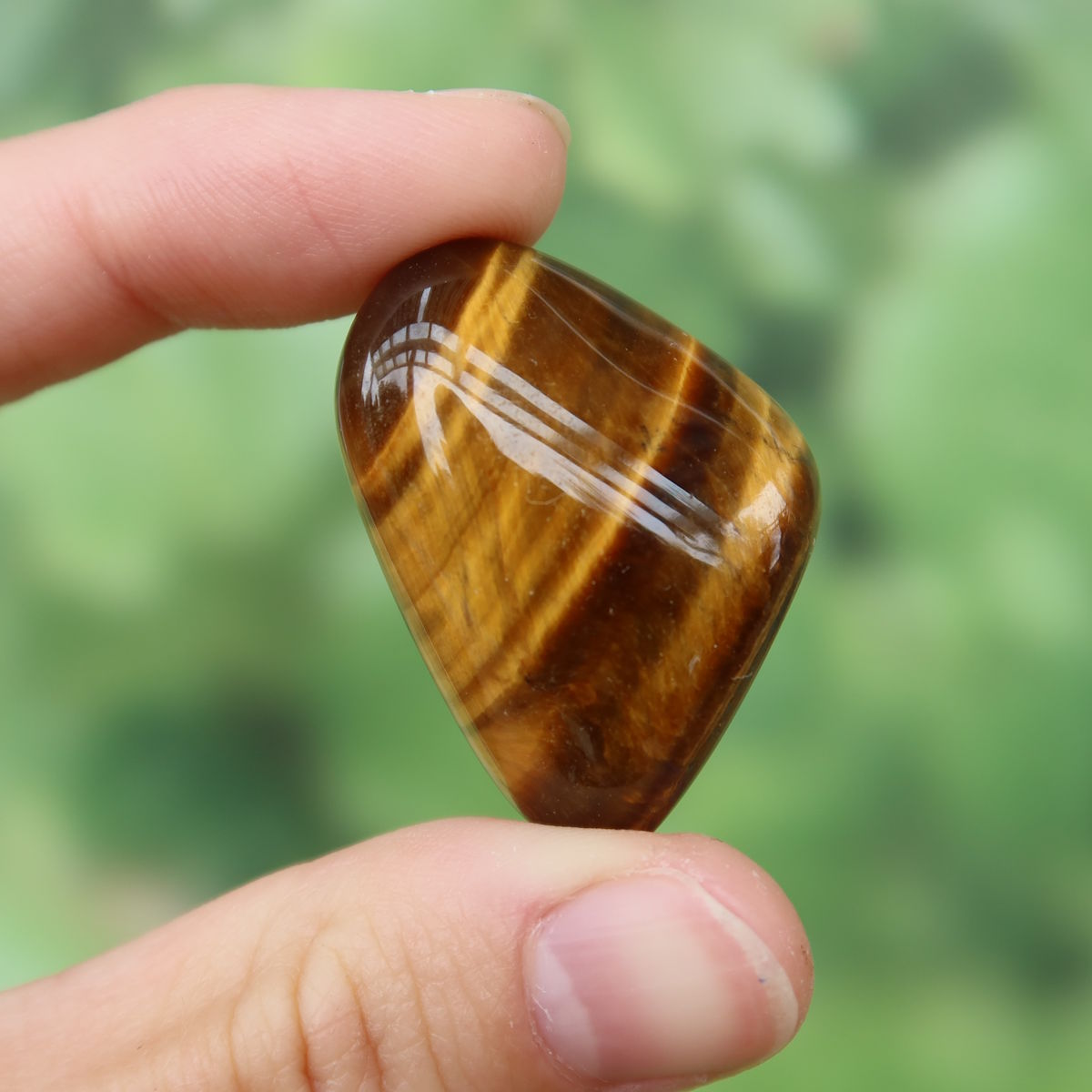 Tigerauge Handschmeichler 30mm - Selbstbewusstsein und Konzentration - Unikat Nr. 2, glänzender goldbrauner Stein in einer Hand gehalten