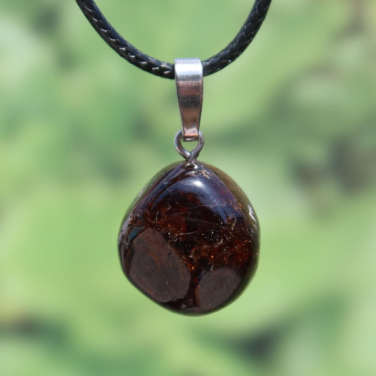 Turmalin Dravit Anhänger mit braunen Nuancen und Silberöse vor grünem Hintergrund, 20mm, für Selbstsicherheit und Entspannung.