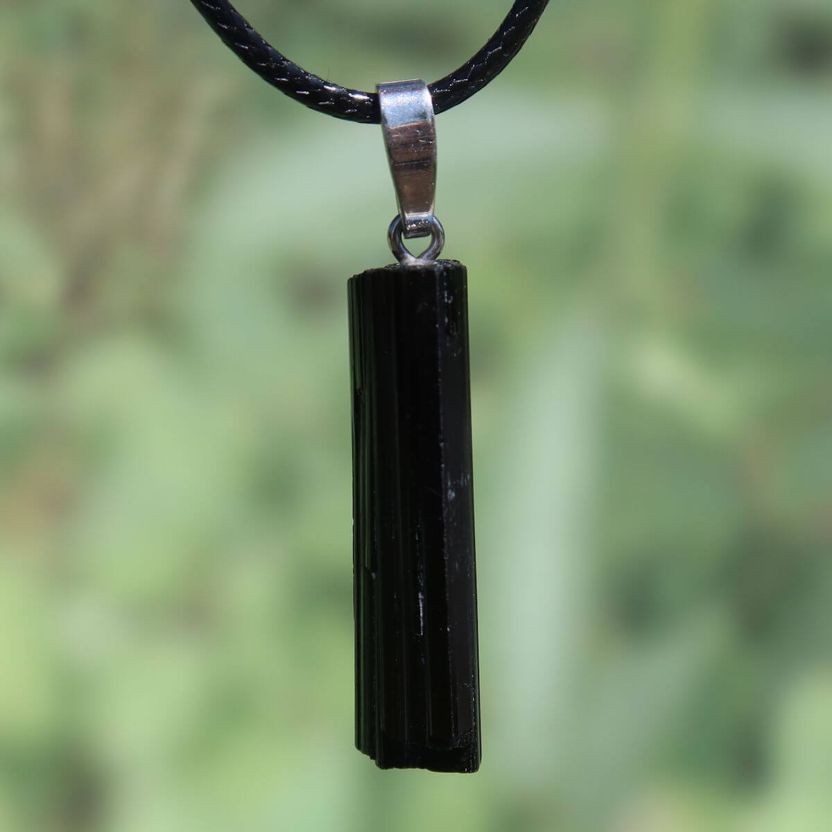 Black Tourmaline Schörl pendant with silver loop, 36mm unique piece for protection and distinction, displayed on a green background.