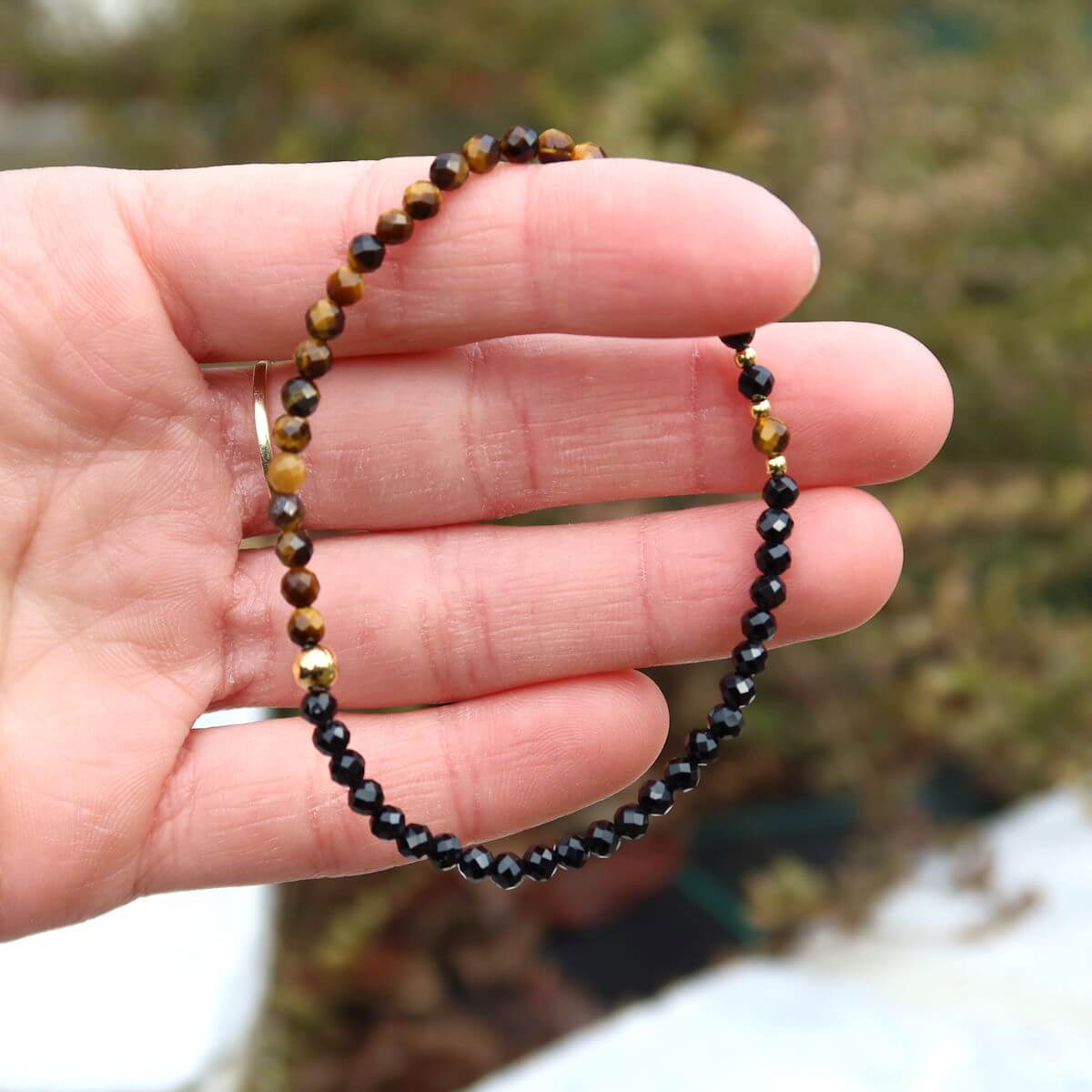 Handmade faceted tiger eye and black tourmaline gemstone bracelet on wrist, 17cm length, showcasing detailed craftsmanship and sparkling stones.