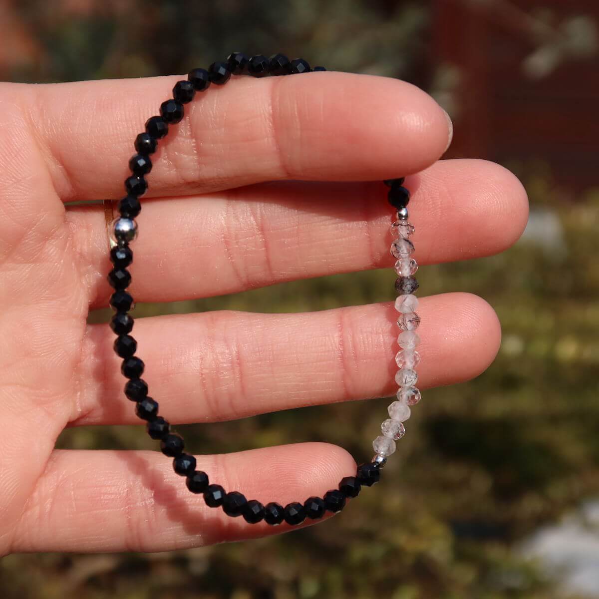 Hand holding faceted black Tourmaline and Tourmaline Quartz gemstone bracelet, handmade, 17cm long.