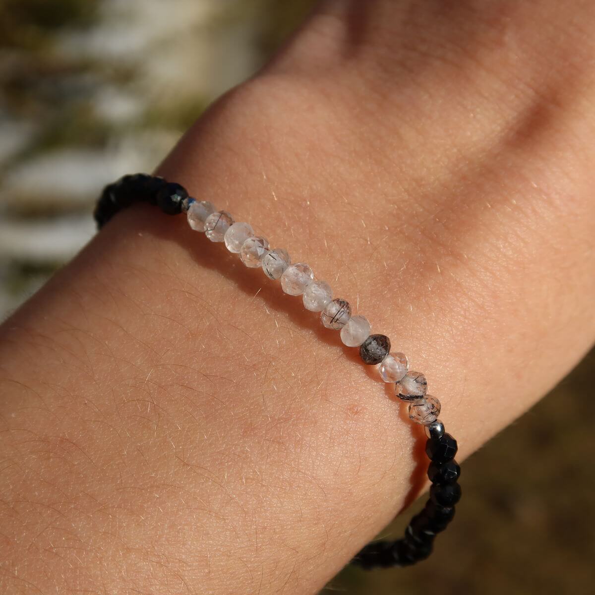 Hand holding faceted black Tourmaline and Tourmaline Quartz gemstone bracelet, handmade, 17cm long.