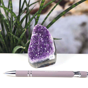 Uruguay Amethyst Mini Geode - 9x6x7cm - Harmonie und Entspannung – extra dunkler Qualität - NR 49 next to a pen on a desk.