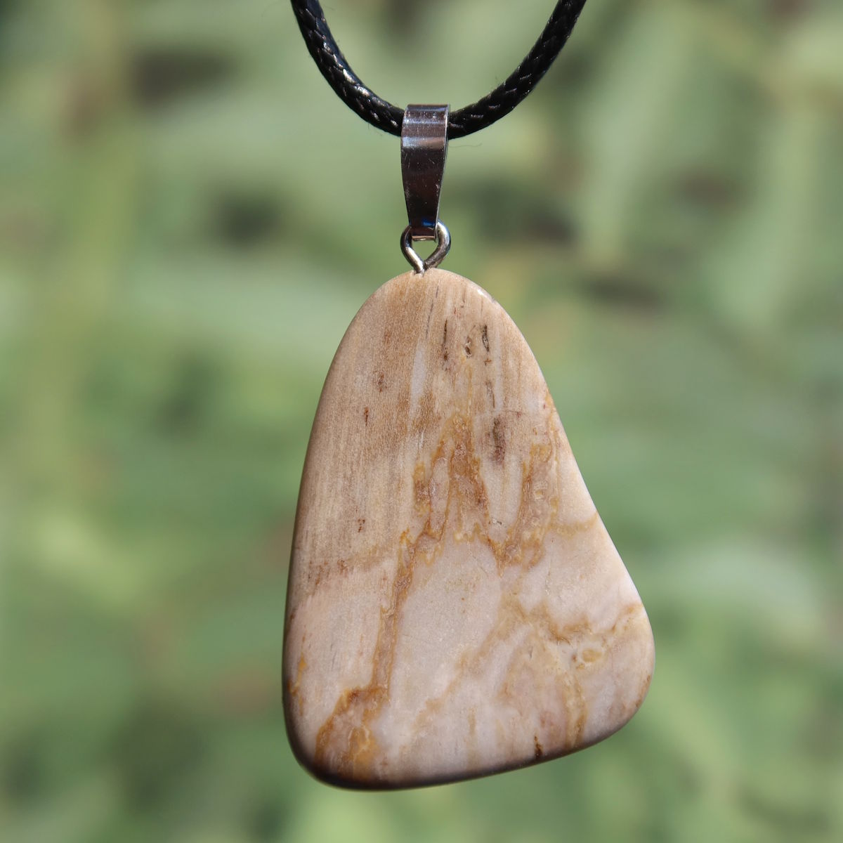 Versteinertes Holz Anhänger - Erdung und Stabilität - UNIKAT Nr. 13 vor grünem Hintergrund