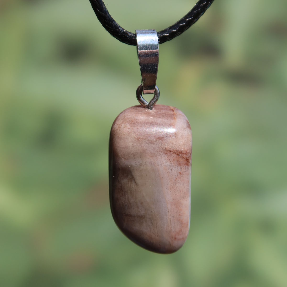 Versteinertes Holz Anhänger - Erdung und Stabilität - UNIKAT Nr. 9 in natürlicher Schönheit vor grünem Hintergrund