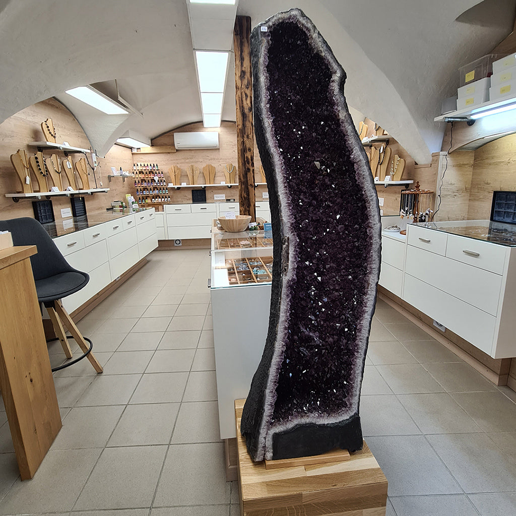 Large amethyst geode displayed in a modern kitchen showroom with white cabinets and wooden accessories