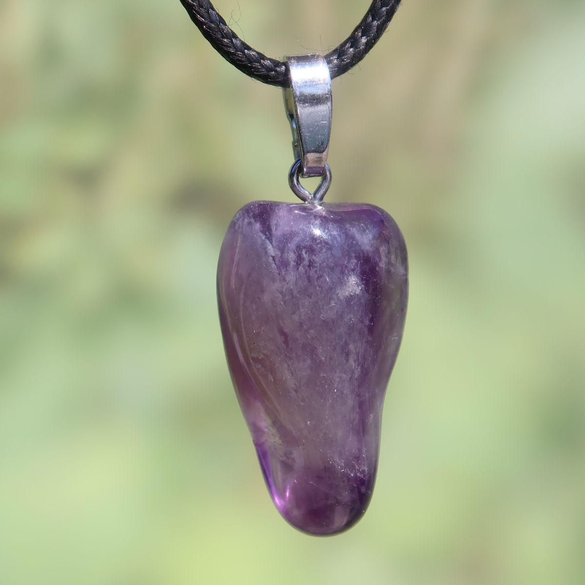 Amethyst Anhänger - Schutz und Spiritualität - UNIKAT Nr. 23 an einem schwarzen Halsband vor unscharfem Hintergrund.