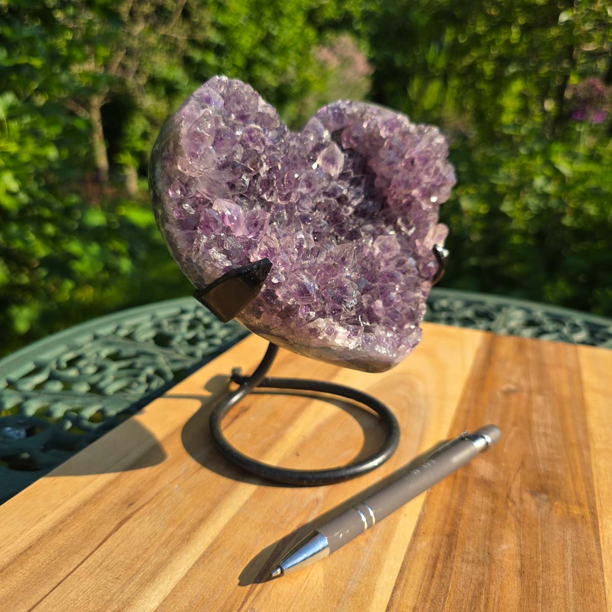 Amethyst Druse Amethyst Geode in Herzform mit Metallsockel 16x12x13cm - NR-38 auf einem Holztisch.