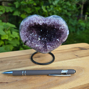 Amethyst Druse Amethyst Geode in Herzform mit Metallsockel 11x10x9cm - NR-60 auf Holzstand, Blick auf Kristallstruktur.