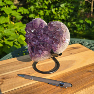 Amethyst Druse Amethyst Geode in Herzform mit Metallsockel 15x15x12cm - NR-41 auf einem Tisch mit einem Stift.