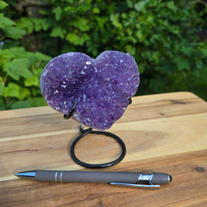Amethyst Druse Amethyst Geode in Herzform mit Metallsockel 12x10x9cm - NR-52 auf Holztisch mit Stift
