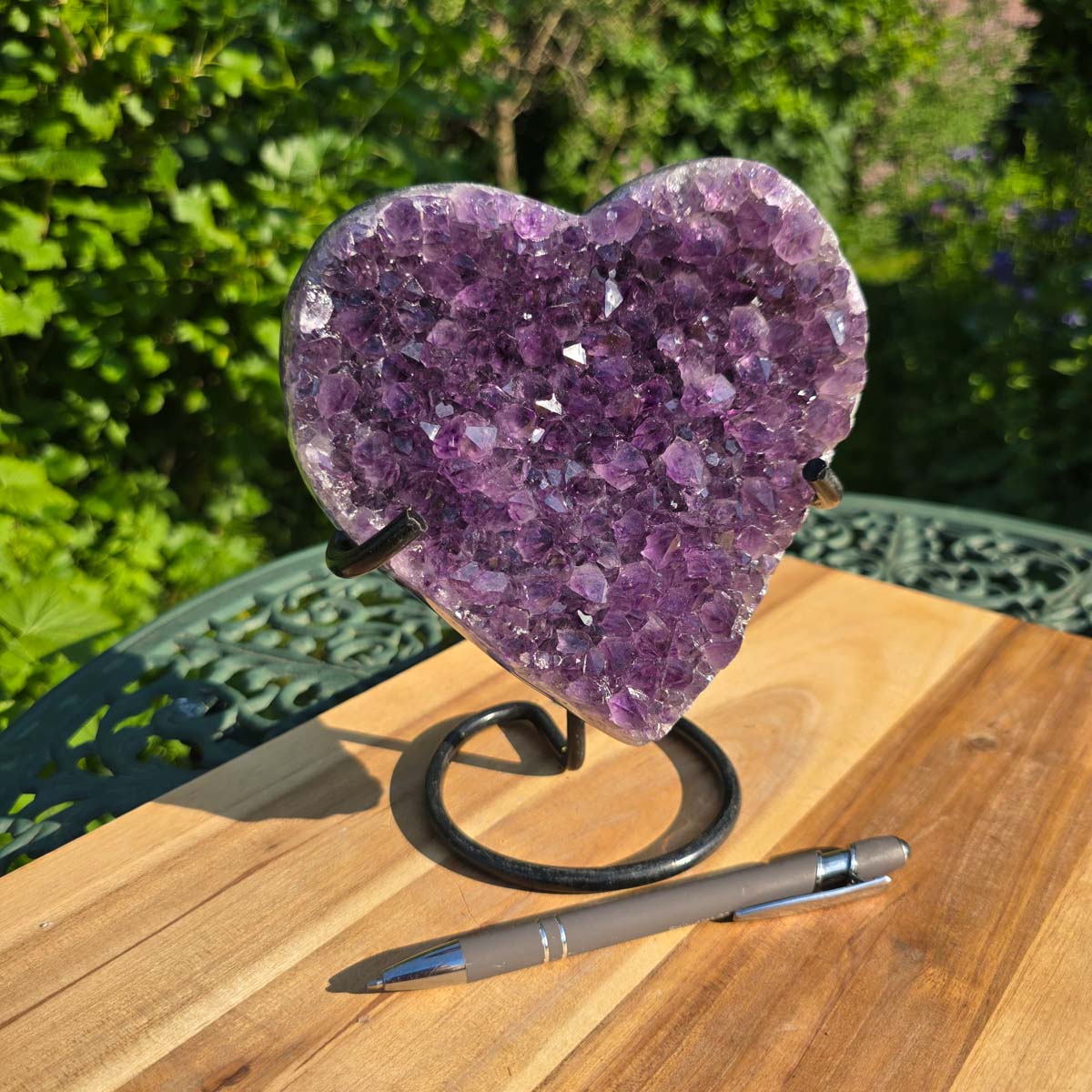 Amethyst Druse Amethyst Geode in Herzform mit Metallsockel 18x16x10cm - NR-43 auf einem Holz-Tisch präsentiert