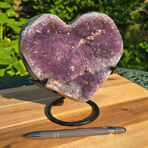 Amethyst Druse Amethyst Geode in Herzform mit Metallsockel 18x17x13cm - NR-31 auf Holzunterlage mit Kugelschreiber