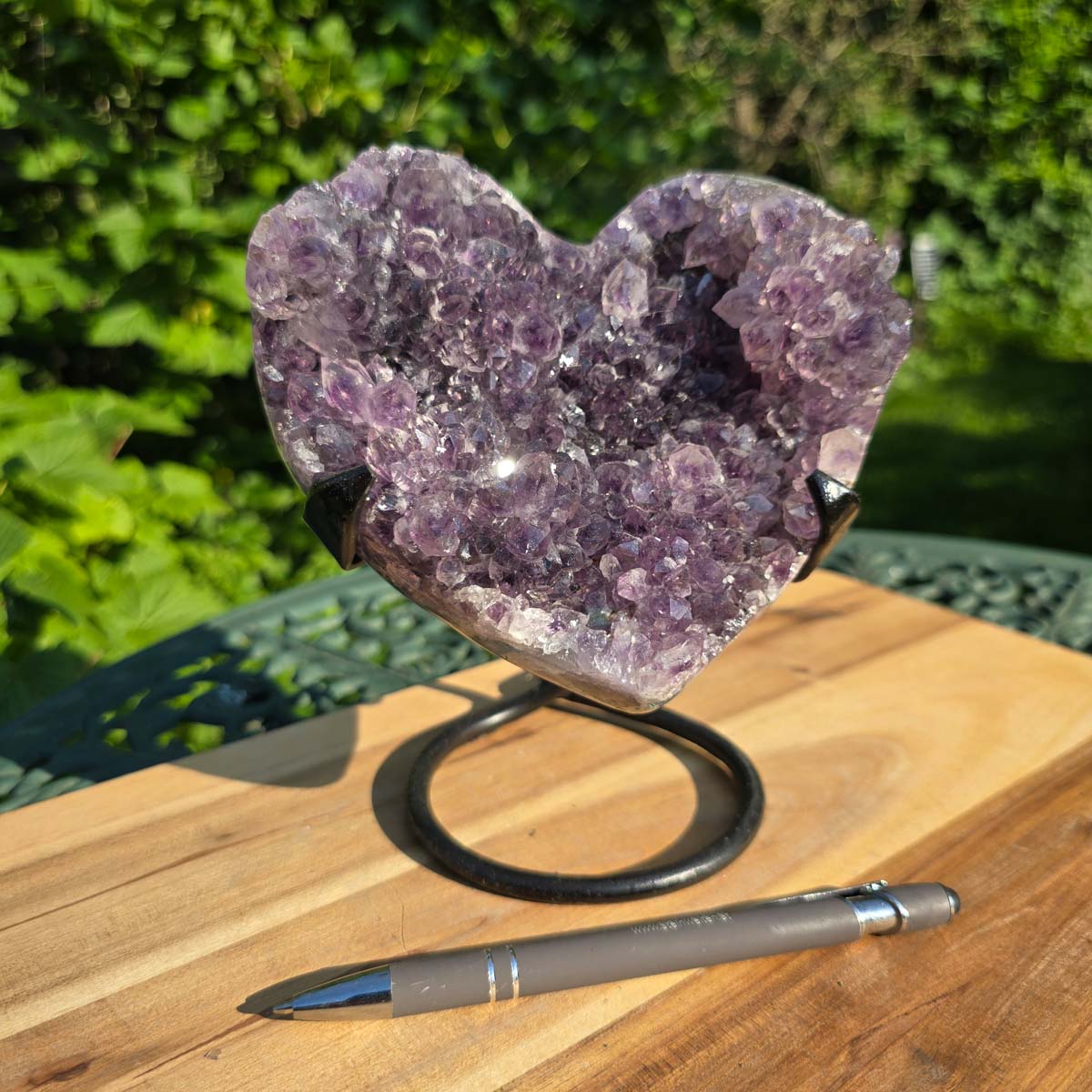 Amethyst Druse Amethyst Geode in Herzform mit Metallsockel 16x12x13cm - NR-38 auf einem Holztisch.