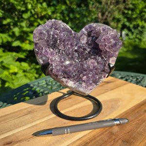 Amethyst Druse Amethyst Geode in Herzform mit Metallsockel 16x12x13cm - NR-38 auf einem Holztisch.