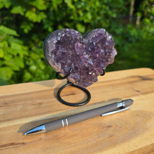 Amethyst Druse Amethyst Geode in Herzform mit Metallsockel 10x9x7cm - NR-58 auf stabiler Halterung vor grünem Hintergrund.