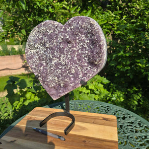 Amethyst Druse Amethyst Geode in Herzform mit Metallsockel 40x34x12cm - NR-26 auf einem Tisch mit Stift.