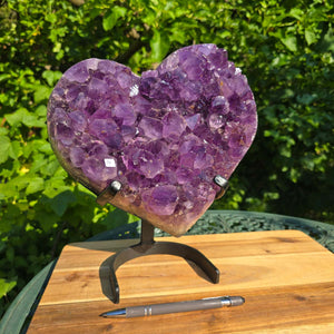 Amethyst Druse Amethyst Geode in Herzform mit Metallsockel 28x24x12cm - NR-14 auf einem Tisch mit Stift