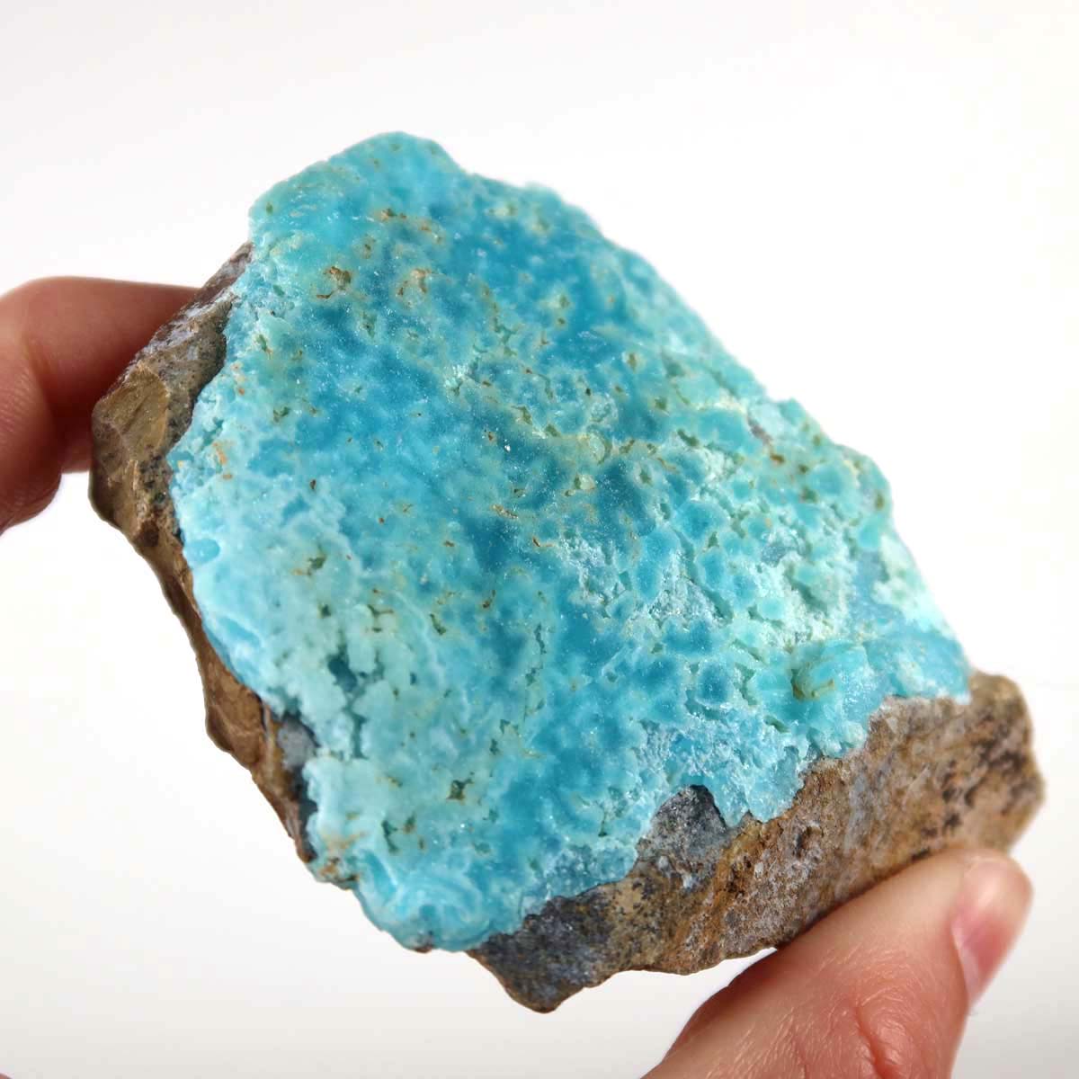 Hand holding a turquoise blue Hemimorphite raw stone, showcasing natural colors and unique crystal structure, perfect for collectors.
