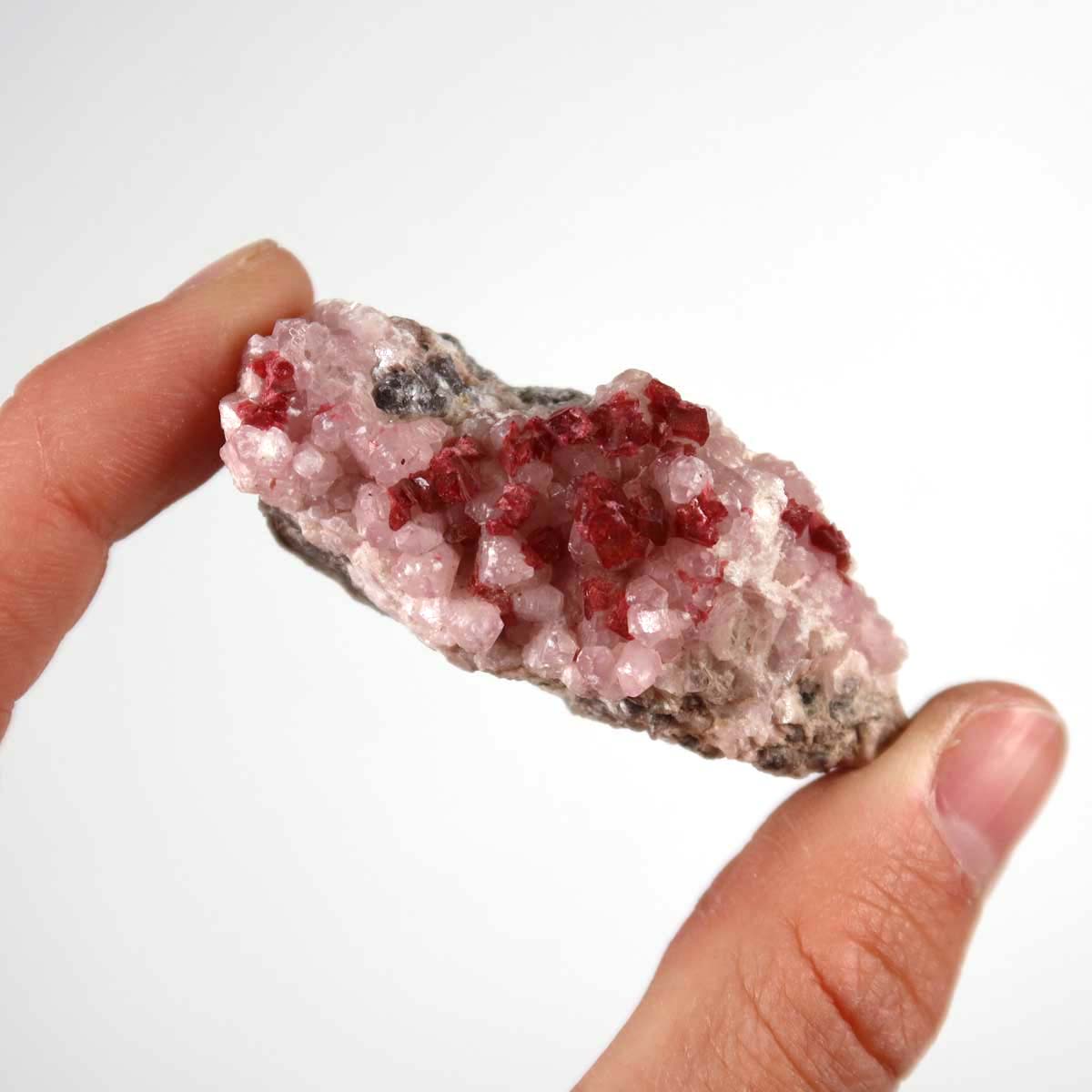 Hand holding raw Kobalt Calcit mineral stone with pink crystal structure, showcasing its natural beauty and unique pattern.