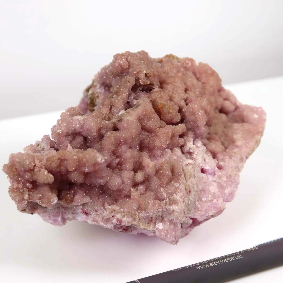 Kobalt Calcit raw mineral stone from Morocco in natural pink, showcasing unique crystal structure next to a pen for scale.