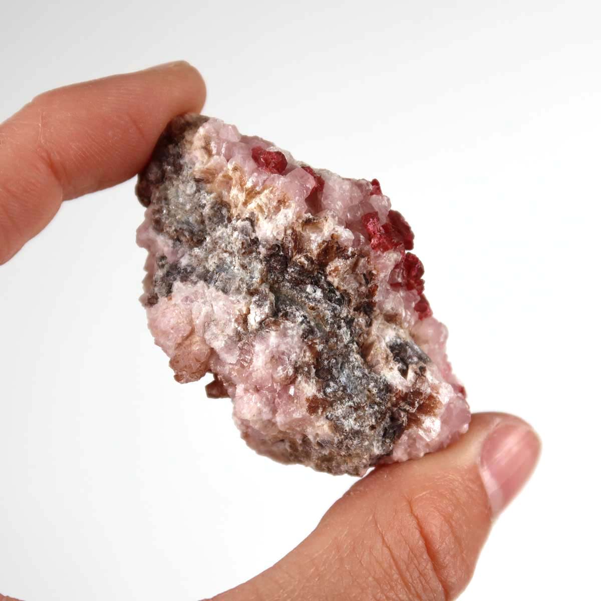 Hand holding raw Kobalt Calcit mineral stone with pink crystal structure, showcasing its natural beauty and unique pattern.