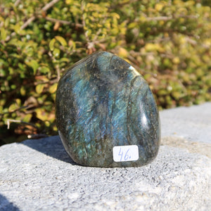 Labradorit Freiform poliert - 7x6cm - Intuition und Kreativität Nr.46, schimmernd in Blau- und Grüntönen im Sonnenlicht.