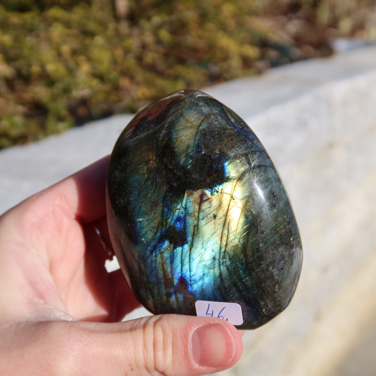 Labradorit Freiform poliert - 7x6cm - Intuition und Kreativität Nr.46, schimmernd in Blau- und Grüntönen im Sonnenlicht.