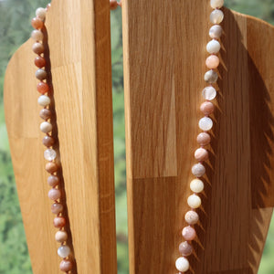 Mondstein Kette in sanften Farben auf einem Holzständer präsentiert, strahlt Eleganz und Leichtigkeit aus.