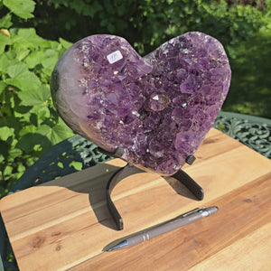 Amethyst Druse Amethyst Geode in Herzform mit Metallsockel 23x20x13cm - NR-19 auf einem Tisch präsentiert