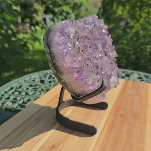 Amethyst Druse Amethyst Geode in Herzform mit Metallsockel 18x18x10cm - NR-7 auf einem Tisch im Freien.