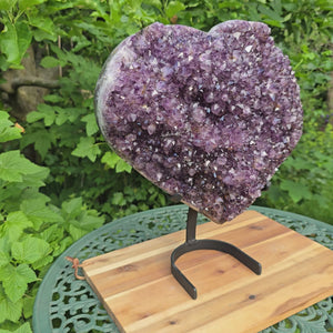 1A Amethyst Herzen (Druse - Geode) mit Metallsockel 38x32x16cm - NR-65 auf stabiler Halterung im grünen Garten.