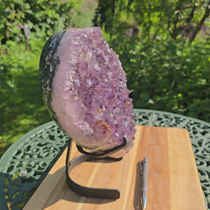 Amethyst Druse Amethyst Geode in Herzform mit Metallsockel 26x24x14cm - NR-21 auf einem Tisch im Freien