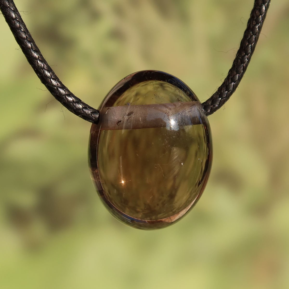 Rauchquarz gebohrt - Anti Stress Stein - Nr. 4 an einem schwarzen Halsband im Licht glänzend.