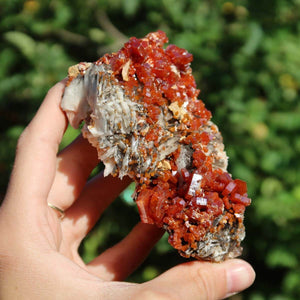 Vanadinit auf Baryt - Natürliche Kristallstufe aus Marokko 9x6x4,5cm - 0,36kg Nr.67 in Hand gehalten, leuchtende rot-orange Farben.