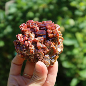 Vanadinit - Natürliche Kristallstufe aus Marokko 7,5x6,5x5cm - 0,48kg Nr.21 in Hand mit grünem Hintergrund.
