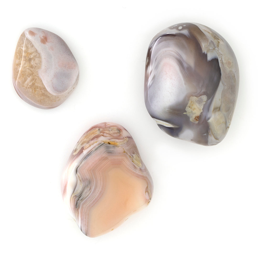Achat Botswana rosa - Handschmeichler naturbelassene Trommelsteine in Grau-, Rosa- und Brauntönen auf einem Holzteller